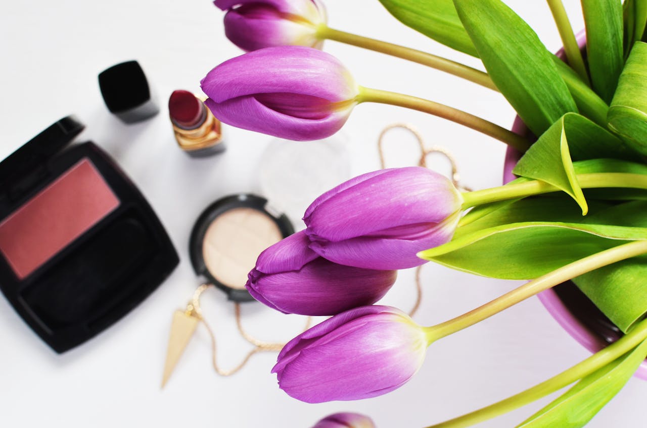 why-choose-us Purple tulips and makeup create a stylish beauty flat lay.