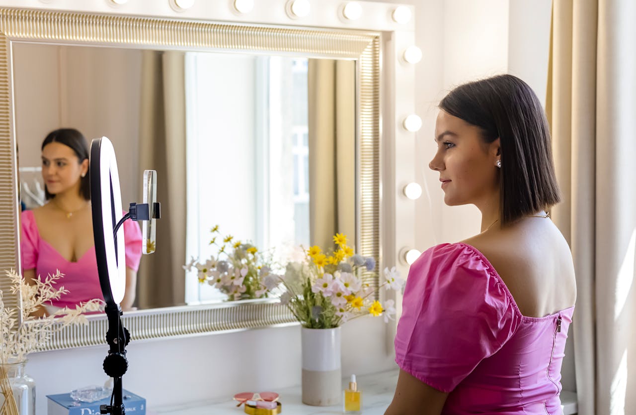 gallery-3 A young woman records a vlog using a ring light in front of a stylish mirror.