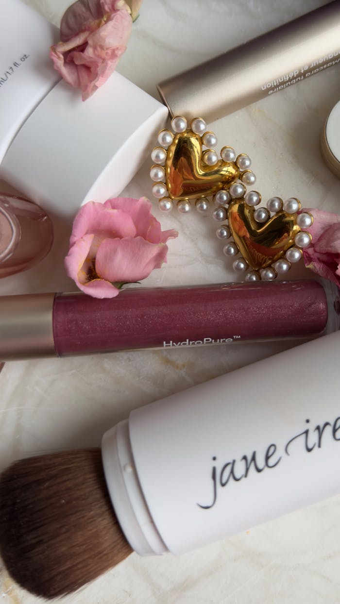 gallery-2 Flat lay of elegant beauty products and flowers with gold heart accessory.
